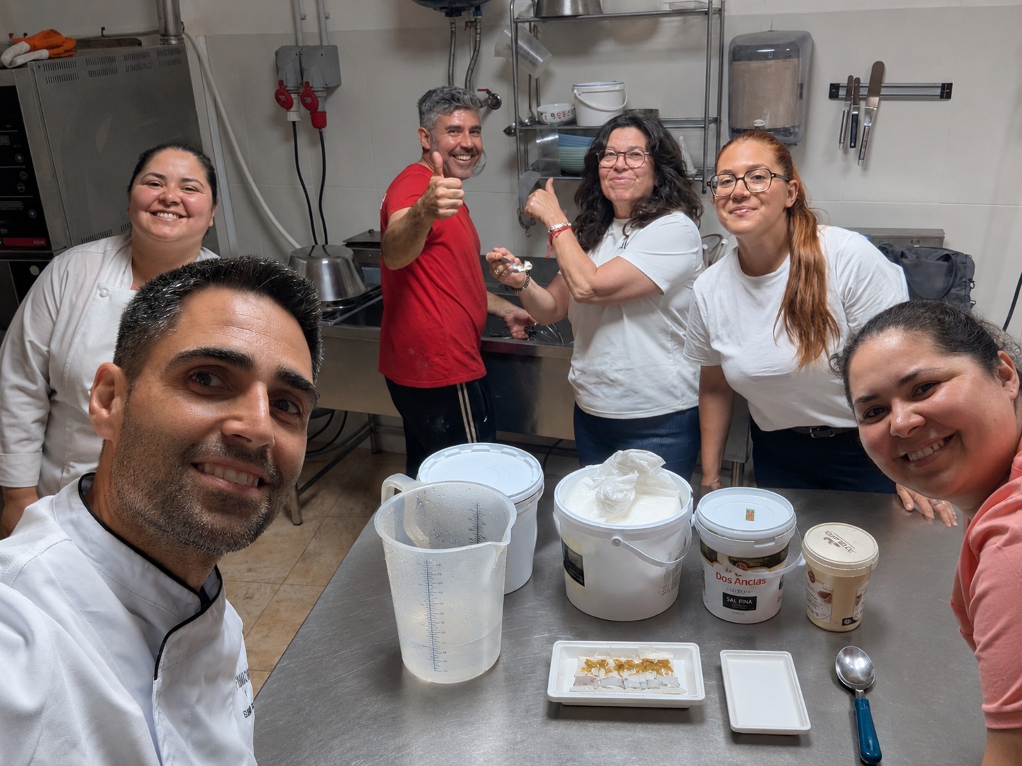 Grupo de alumnos sonriendo junto al profesor durante una clase práctica en el obrador de heladería artesanal